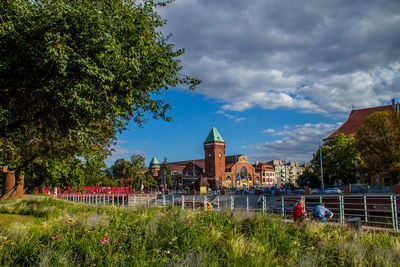 View of trees and buildings against cloudy sky