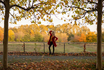 Rear view of woman standing by trees during autumn