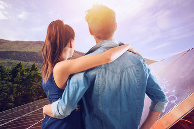 Rear view of couple standing on mountain against sky