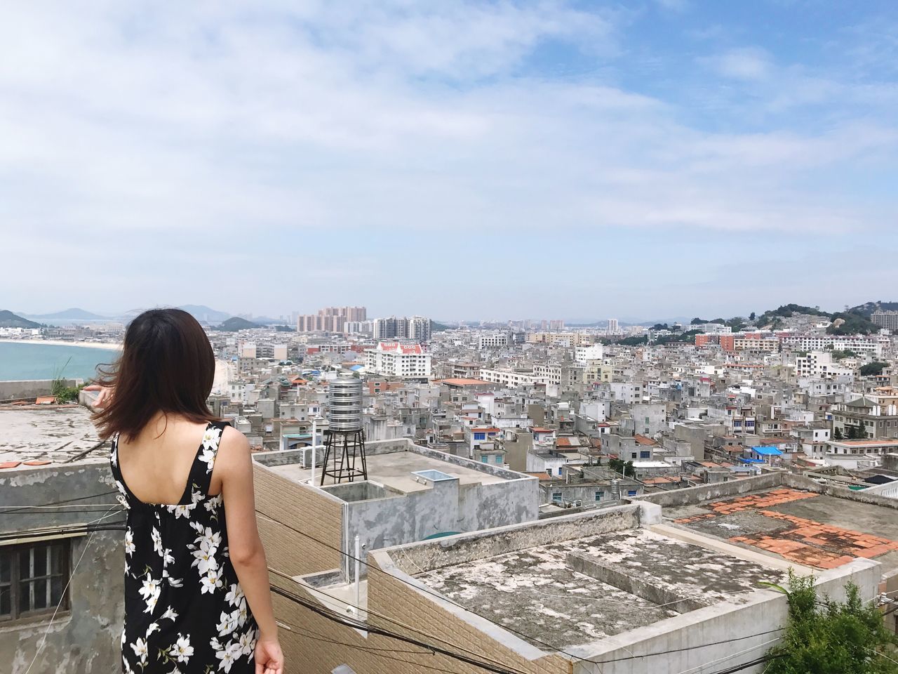 built structure, architecture, building exterior, real people, rear view, one person, sky, cityscape, day, outdoors, mountain, lifestyles, standing, city, women, young adult, young women, people