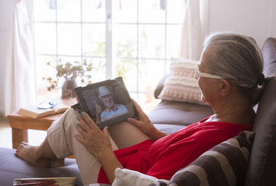 Senior woman holding digital tablet while sitting at home