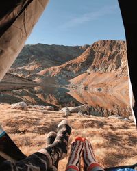 Low section of people on mountain against sky