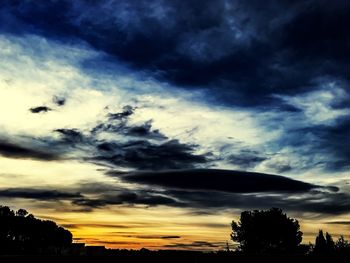 Silhouette of trees against cloudy sky