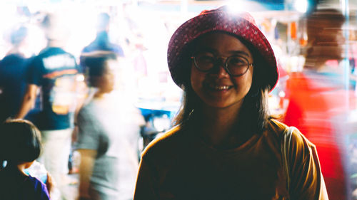 Portrait of smiling young woman standing in illuminated market