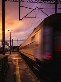 Train at railroad station against sky during sunset