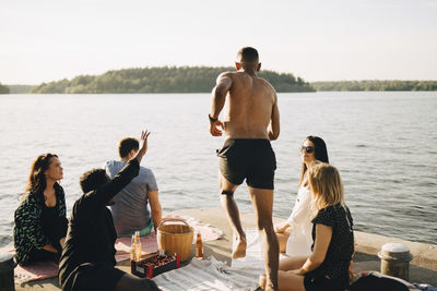 People standing by lake against clear sky