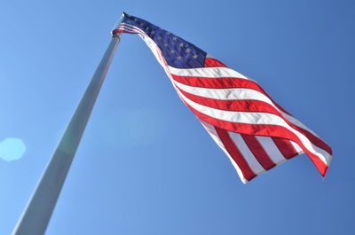 Low angle view of american flag waving against clear blue sky