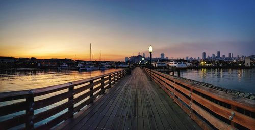 View of pier on river at sunset