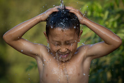 Shirtless boy enjoying while bathing with flowing water
