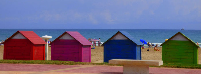 Colorful huts at beach against sky