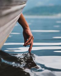 Cropped hand from boat touching water in dal lake