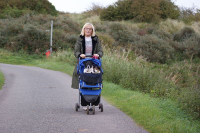 Portrait of mature woman carrying dogs in baby stroller