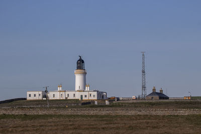 Lighthouse by building against sky