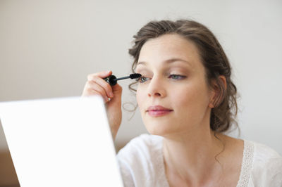 Woman looking in mirror applying mascara