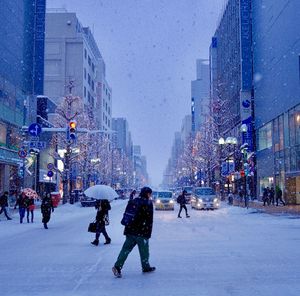 People on snow covered city against sky