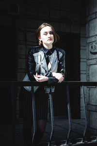 Portrait of young woman standing at balcony during sunny day