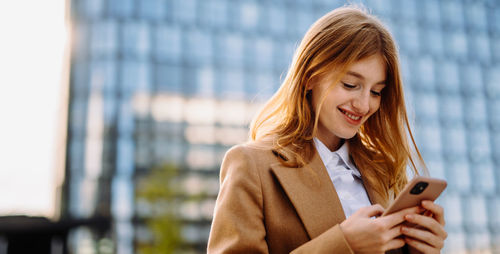 Professional businesswoman smiling and using mobile phone in formal attire