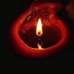 Close-up of lit candle against black background