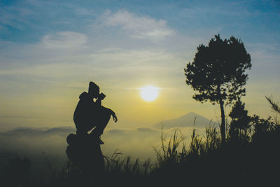 Silhouette man standing on field against sky during sunset