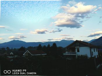 Houses and mountains against cloudy sky