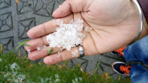 Low section of man holding hailstones on footpath