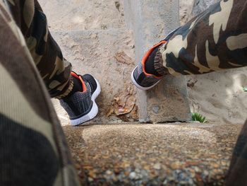 Low section of person in shoes sitting on sand