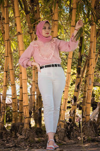 Portrait of woman standing by tree