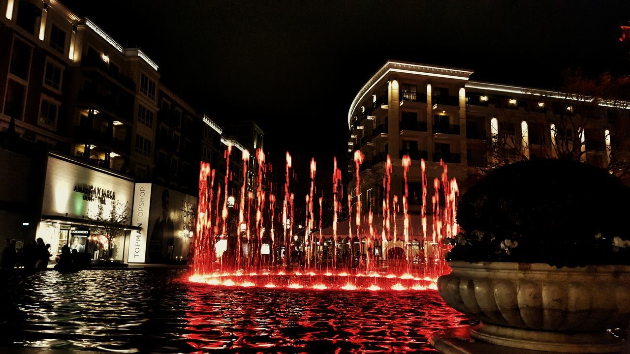 night, illuminated, water, architecture, building exterior, built structure, waterfront, long exposure, reflection, motion, river, sky, city, outdoors, multi colored, no people, building, fountain, street light, light - natural phenomenon