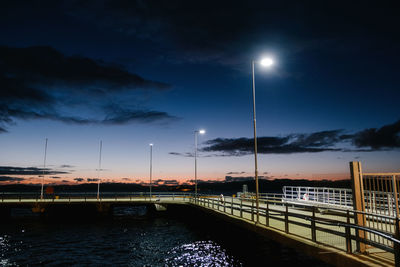 Bridge over river against sky at night