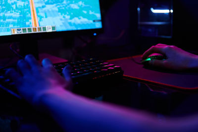 Gamer play computer game, use rgb neon colored keyboard