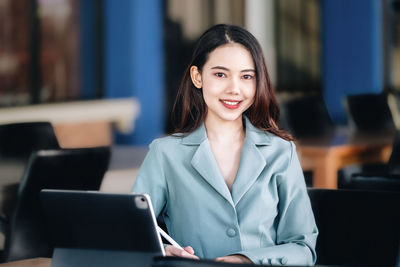 Portrait of young woman using laptop at cafe