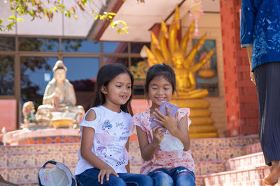 Full length of a smiling girl sitting in temple