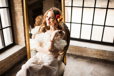 Portrait of young woman standing by window