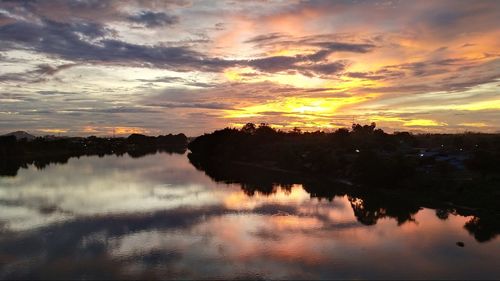 Scenic view of lake against dramatic sky during sunset