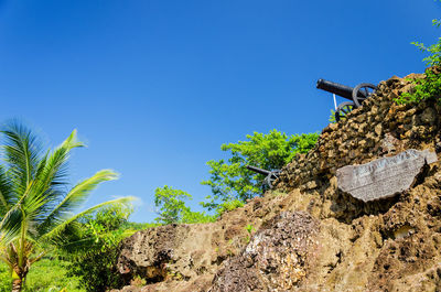 Low angle view of cannons on mountain against clear blue sky