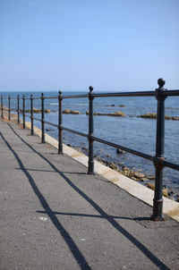 Railing by sea against clear sky