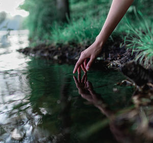 Cropped hand of woman touching water in lake