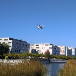 Airplane flying over city against clear blue sky