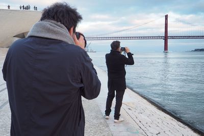 Rear view of man and woman standing on bridge