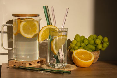 Glass of water with fresh lemon juice with reusable glass straws detox cold tonic water with sunny