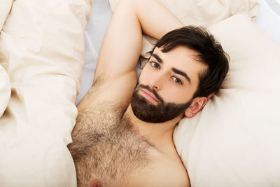 Portrait of young man lying down on bed