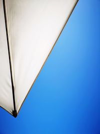 Low angle view of parasol against clear blue sky