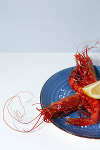 Tasty seafood of cooked red shrimps with fresh lemon slices and coarse salt on white background