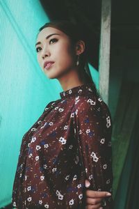 Close-up of beautiful young woman standing against wall