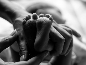 Cropped hands of woman holding newborn baby feet