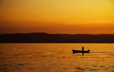 Silhouette man on boat against sky during sunset