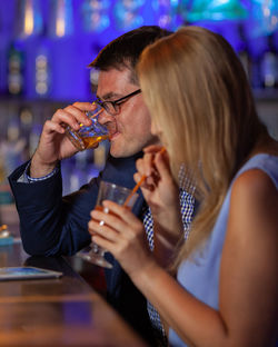 Couple drinking alcohol while sitting at bar