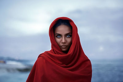 Portrait of young woman with red hair against sky