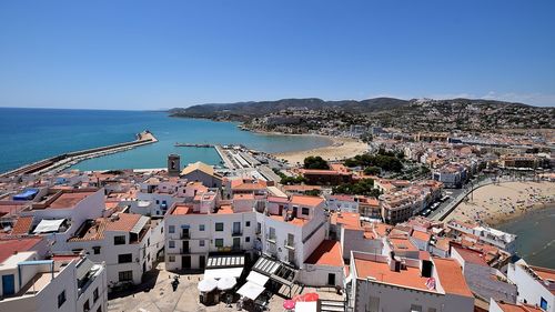 High angle view of townscape by sea against clear sky