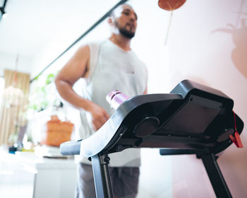 Profile shot of a treadmill with bearded matured man running in the background.